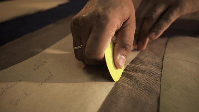 Close up of male fashion tailor hand working on the measurements for the suit design in his workshop.