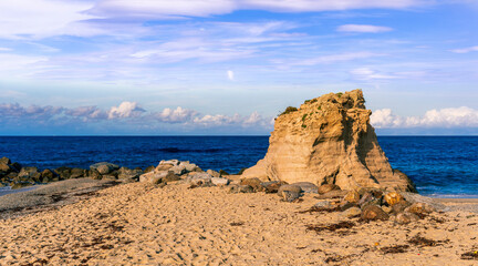 beautiful landscape of white sand beach with amazing waves during scenic sunrise or sunset with beautiful rock cliff , sea surf and nice cloudy sunset sky