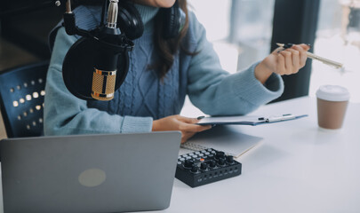 Woman recording a podcast on her laptop computer with headphones and a microscope. Female podcaster...