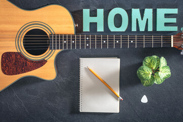 Acoustic guitar, notepad and decorative word Home, top view.