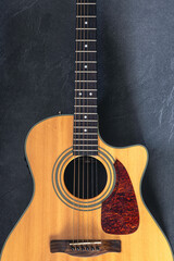 Fototapeta premium Acoustic guitar on a black textured background, top view.