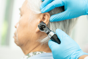 Obraz na płótnie Canvas Audiologist or ENT doctor use otoscope checking ear of asian senior woman patient treating hearing loss problem.