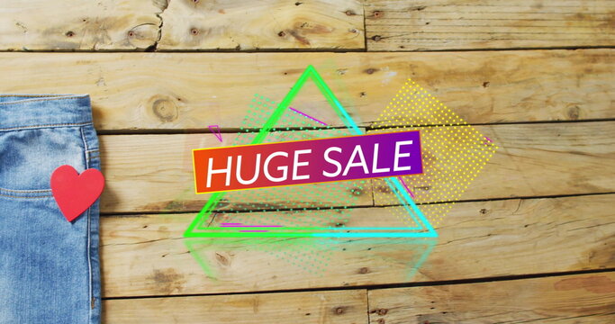 Image of huge sale text over denim trousers on wooden background