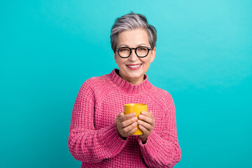Portrait of satisfied senior woman with white gray hairdo wear pink pullover hold cup of tea isolated on turquoise color background