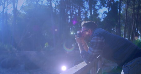 Spots of light against caucasian male photographer clicking pictures with digital camera outdoors