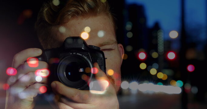 Caucasian male photographer clicking pictures with digital camera against night city traffic