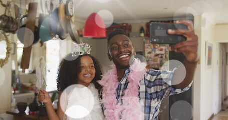 Image of spots over happy african american father with daughter using smartphone