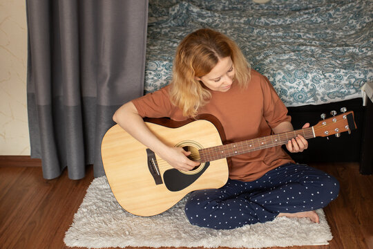 Woman learning guitar, home practice session, acoustic music, musician in training