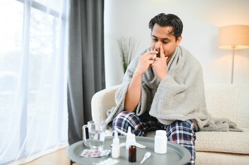 A sick Indian is treated at home and uses a nasal spray. Healthcare concept
