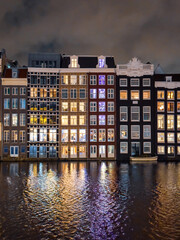 Traditional Dutch construction buildings on Damrak canal at night in Amsterdam in winter