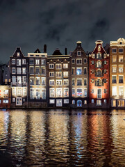 Fototapeta na wymiar Traditional Dutch construction buildings on Damrak canal at night in Amsterdam in winter
