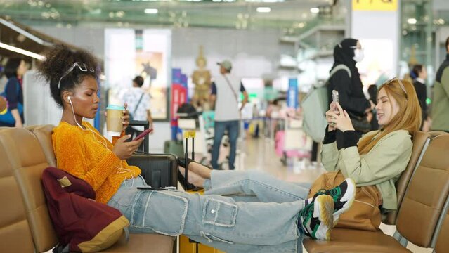 Young woman passengers using mobile phone booking hotel or online remote working during waiting flight at boarding in airport terminal. Attractive girl tourist travel by airplane on holiday vacation.
