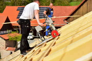 Die Dachlatten eines Steildachs werden vom Dachdecker mit dem Einlattgerät / Einlattblitz mit...