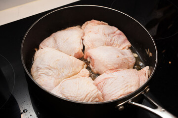 Batch cooking chicken thighs in a pan - obrazy, fototapety, plakaty
