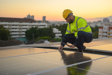 Male engineer works installing solar panels on the roof. Engineer or worker working on solar panels or photovoltaic cells on the roof of a business building.