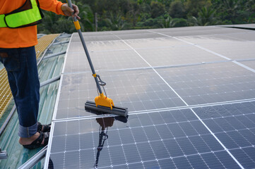 Close-up of the hands and cleaning stick of a worker cleaning a solar panel.