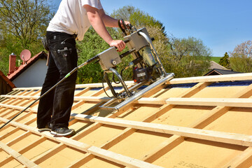 Ein Dachdecker verlegt die Dachlatten eines Steildachs mit dem Einlattgerät / Einlattblitz mit...