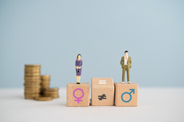 Gender pay equality concept. Miniature of man , woman  on wooden cube block and flipped unequal to...