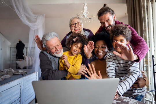 Happy multi-generation diverse family gathering around notebook and having fun during a video call