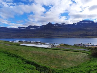 Miasteczko nad fiordem w Islandii. Słoneczny dzień w Islandii. Miasteczko u podnóża gór. 