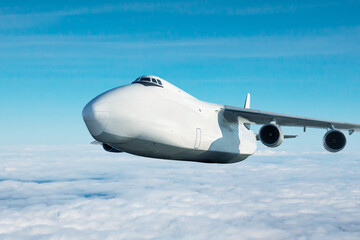 White wide body transport cargo aircraft flying in the air above the clouds