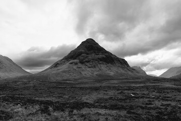 In a striking black and white composition, the iconic peak of Buachaille Etive Mor stands majestic in the Glen Etive region, embraced by the vast expanse of the Scottish Highlands