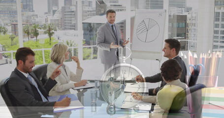 Image of clock over diverse business people at meeting