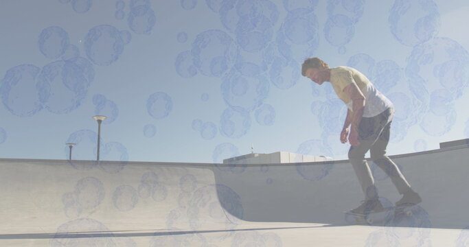 Image of bubbles over caucasian man skateboarding - Powered by Adobe