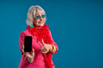 Tech-savvy senior showcasing smartphone and doing thumbs up