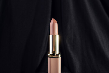 nude matte lipstick on a black background in a pink and gold tube top view, flatlay. Professional...