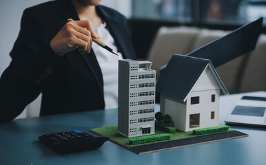 Close up realtor sit at table holds tiny house model, layout of cottage. Real estate purchase, new...