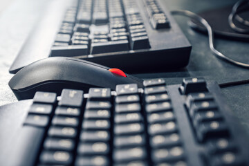 Mouse with red scrolling wheel between keyboards on office desk