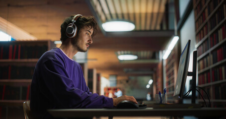 Portrait of a Handsome Student Creating a Business Research Presentation on a Desktop Computer. Young Stylish Male Studying in an University Library with Other People in the Background - obrazy, fototapety, plakaty