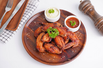 Cooked grilled chicken wings marinated with seasonings Placed on an old wooden tray on a white background