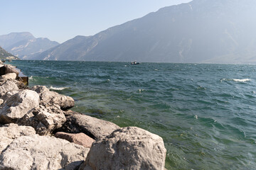 stones on the shore of a lake on a sunny day with mountains in the background