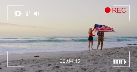 Fototapeta premium Young couple runs with US flag on beach, captured on a camera in 4k.