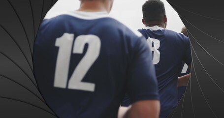 Image of black shapes over male rugby players at stadium