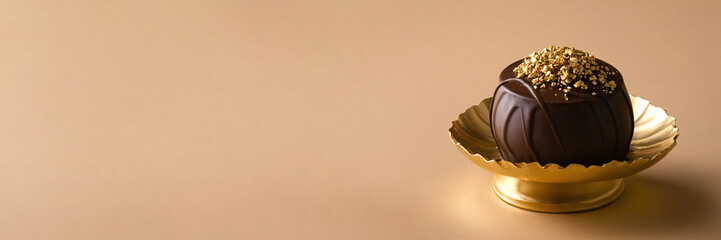 Chocolate candies on a golden stand on a beige background