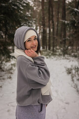 Szczęśliwa młoda dziewczyna, ciepło ubrana spaceruje w lesie, zimą. Terapia lasem, wędrówki...