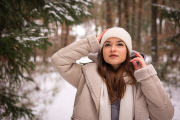 Szczęśliwa młoda dziewczyna, ciepło ubrana spaceruje w lesie, zimą. Terapia lasem, wędrówki leśne.