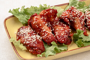 Portion of cooked chicken wings in sauce and sesame seeds
