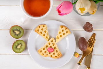 Easter breakfast or brunch. Cute creative decorated soft sweet belgian waffles shaped in form of Easter bunny rabbit, with chocolate eggs and fruits