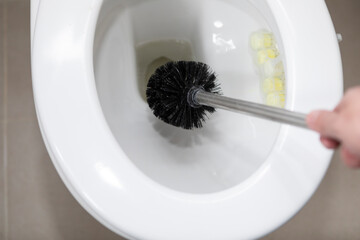 Сlose-up shot of a man cleaning a toilet using a special cleaning product and a brush	