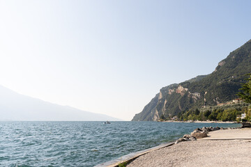 Lake Garda with a beach overlooking the mountains on a sunny day