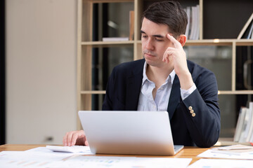 Seriously irritated businessman with eyes closed, migraine headache at work, temple massage, feeling tired, chronic work stress, trying to remember important information.