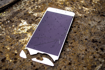 Broken phone screen on rusty surface