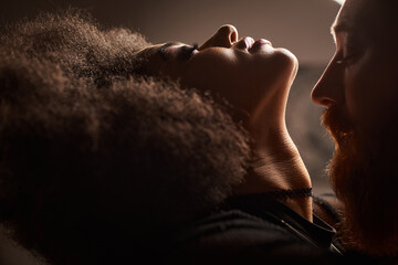 portrait of african american woman with curly hair seducing bearded man with red hair, sexy couple