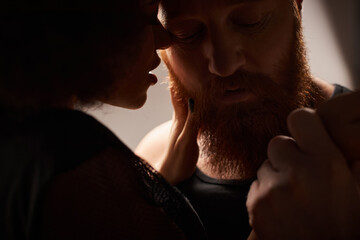 silhouette of african american woman with curly hair seducing bearded man with red hair, sexy couple