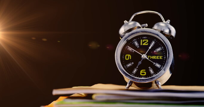 Image of glowing light over alarm clock on stack of books