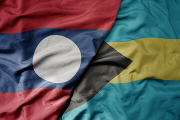 big waving national colorful flag of bahamas and national flag of laos.